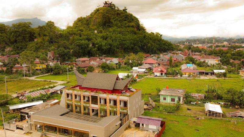 Santai Toraja buildings among rice fields below a green hill